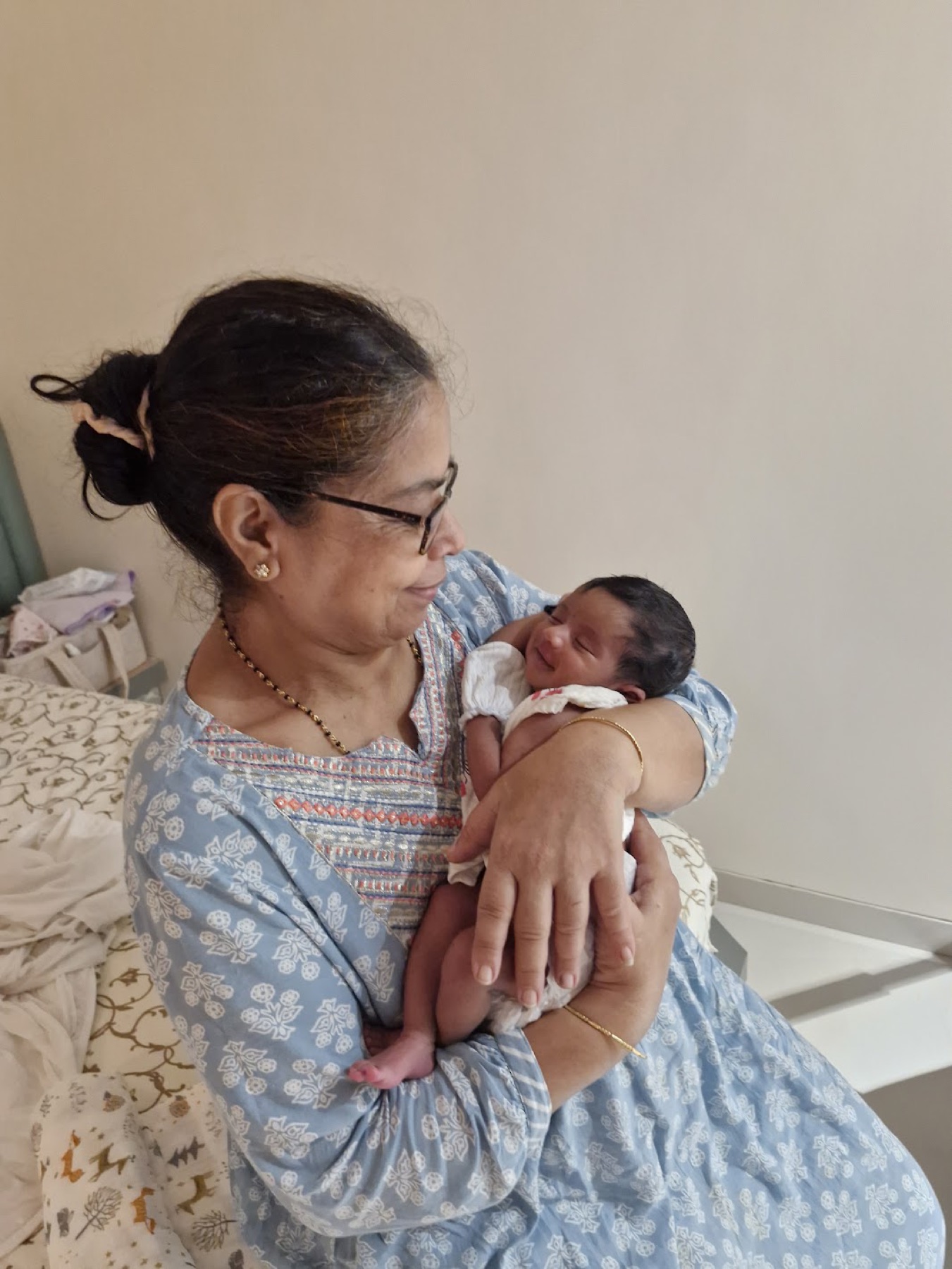 Adira resting in her Granny's arms while Granny smiles down at her.