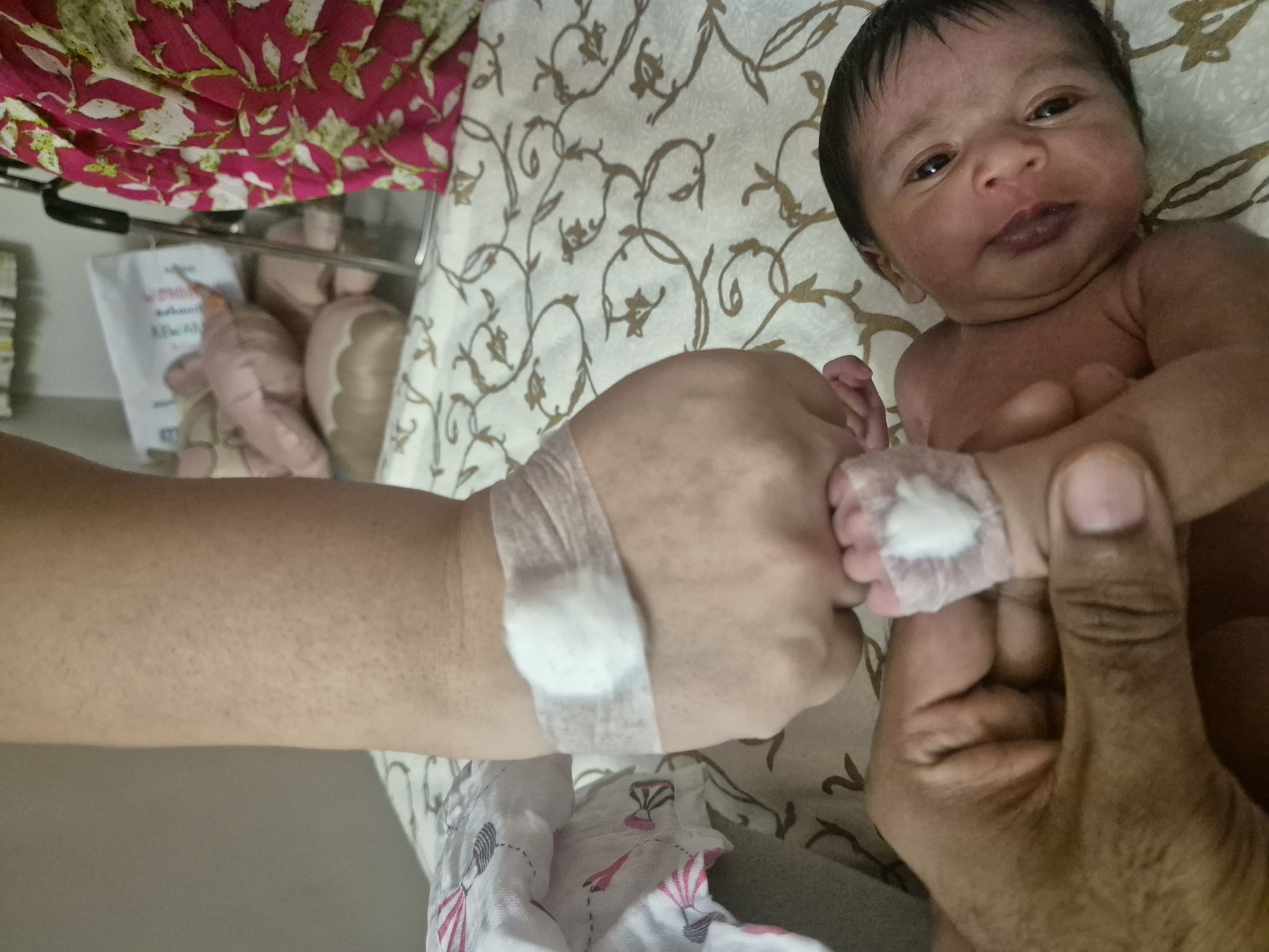 Adira lying on a bed at home with a small bandage on her hand after a blood test.