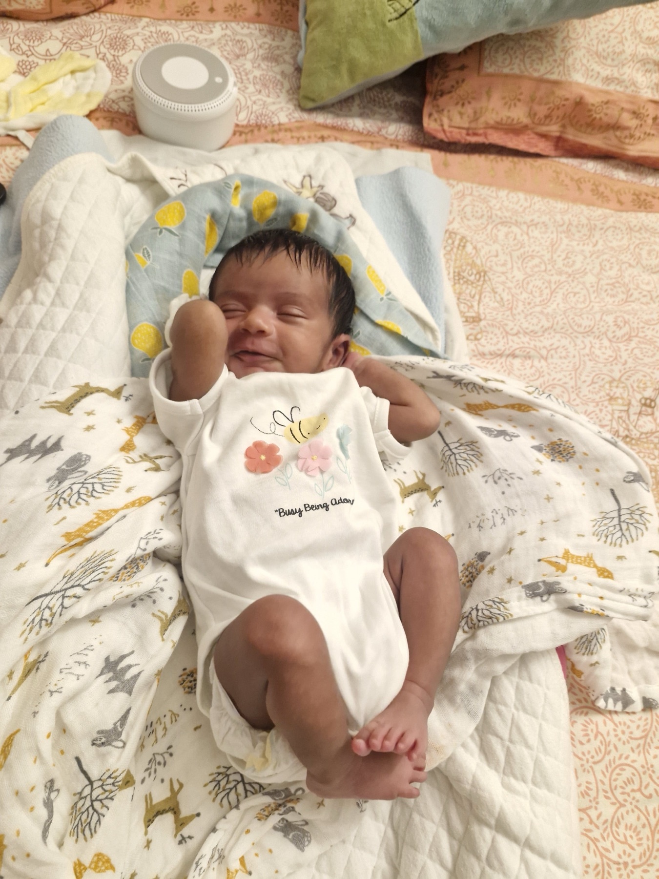 Adira resting on a bed at home with one arm raised beside her face.