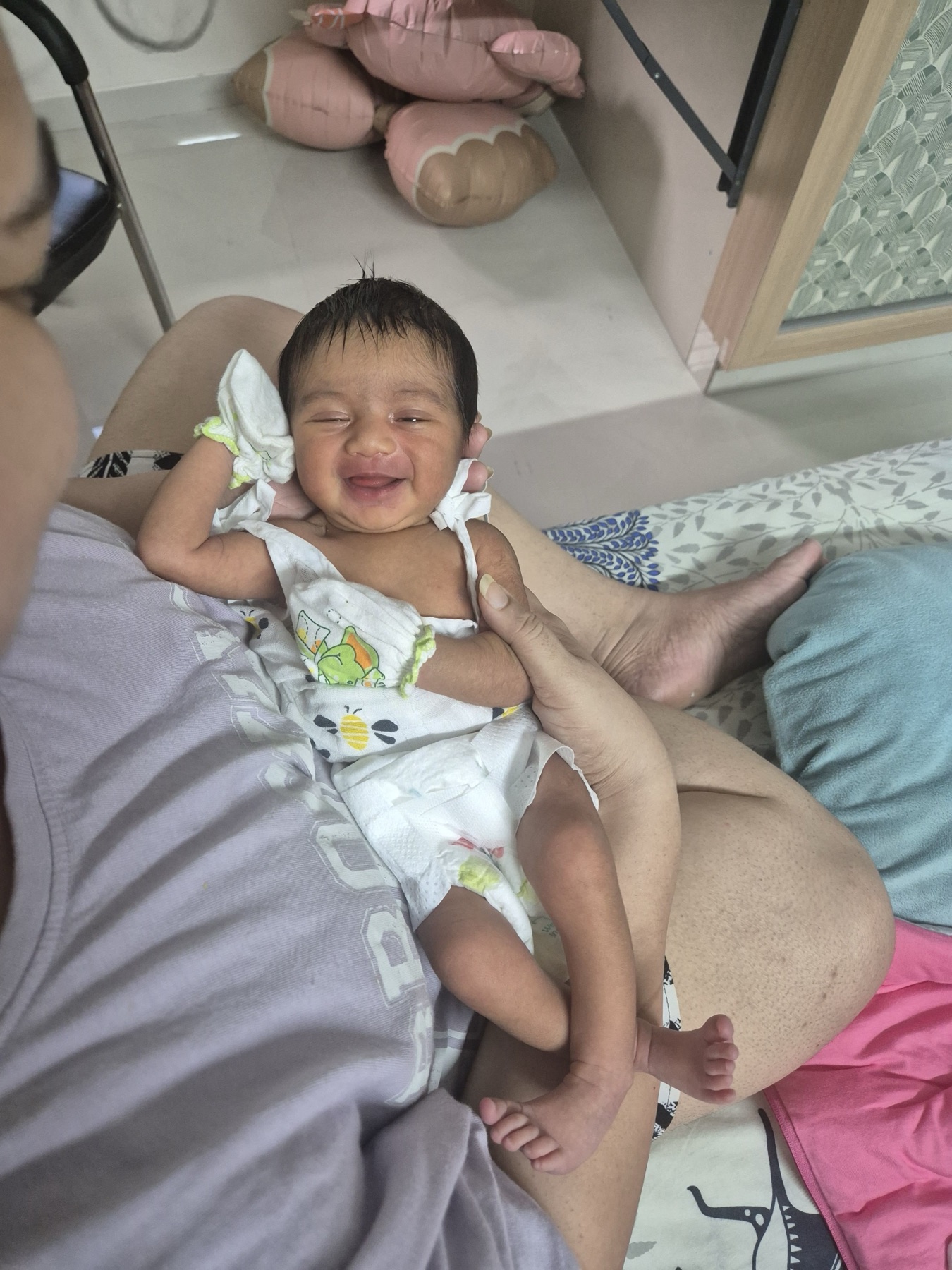 Adira smiling while being held at home.