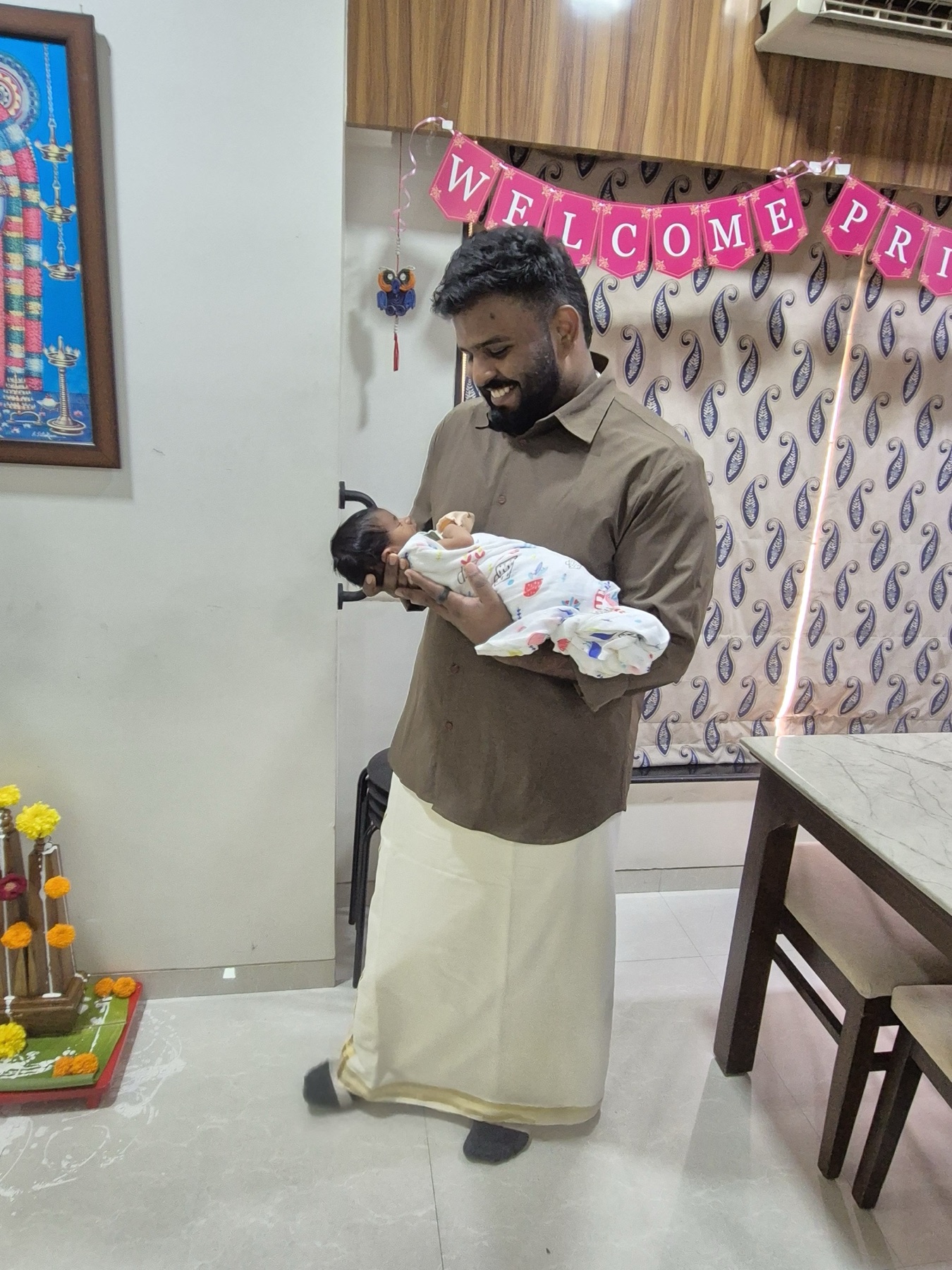 Uncle Pranu holding Adira beneath a Welcome Princess banner.